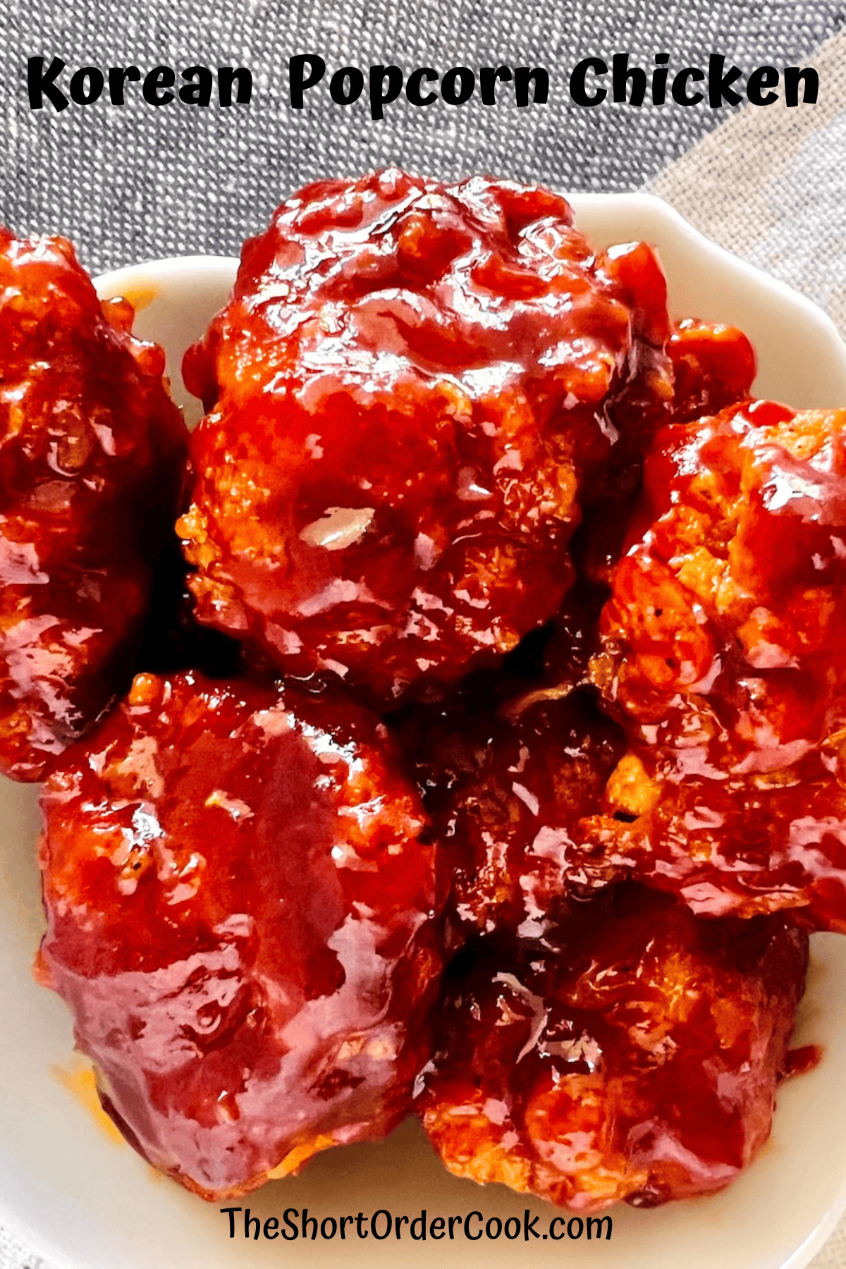 Gochujang flavored Korean sauce tossed over popcorn chicken pieces and stacked in a bowl.