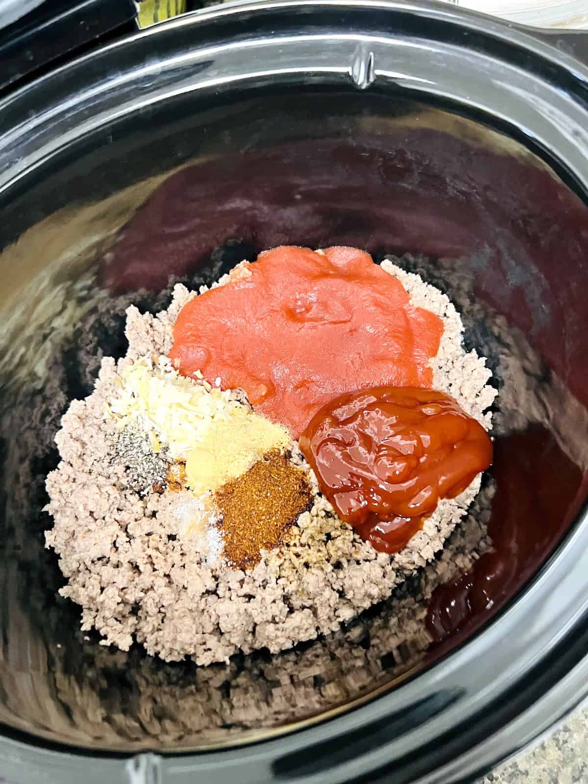 Adding everything to the Crockpot insert to make hot dog chili.