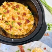 Slow Cooker Loaded Chicken & Cauliflower Casserole in the CrockPot insert topped with cheese bacon and green onions.