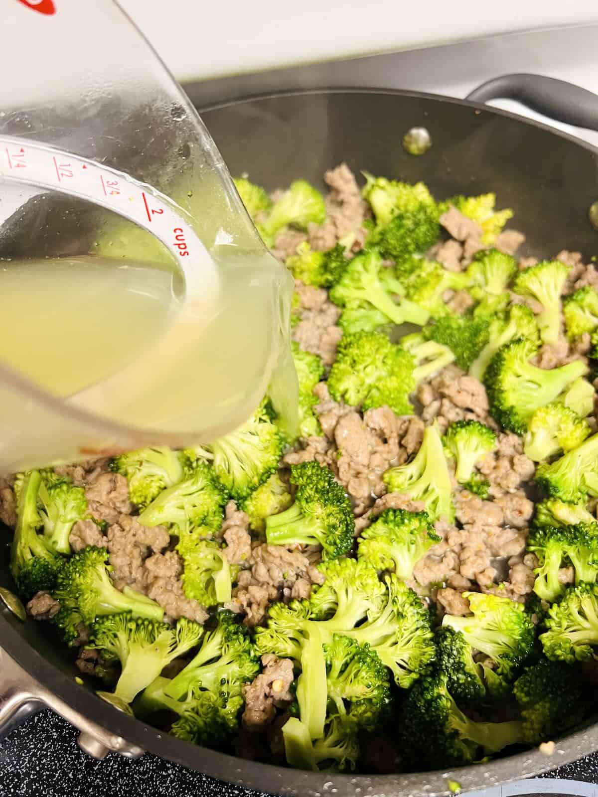 Italian Sausage and Broccoli Pasta Pouring in starchy pasta water to skillet.