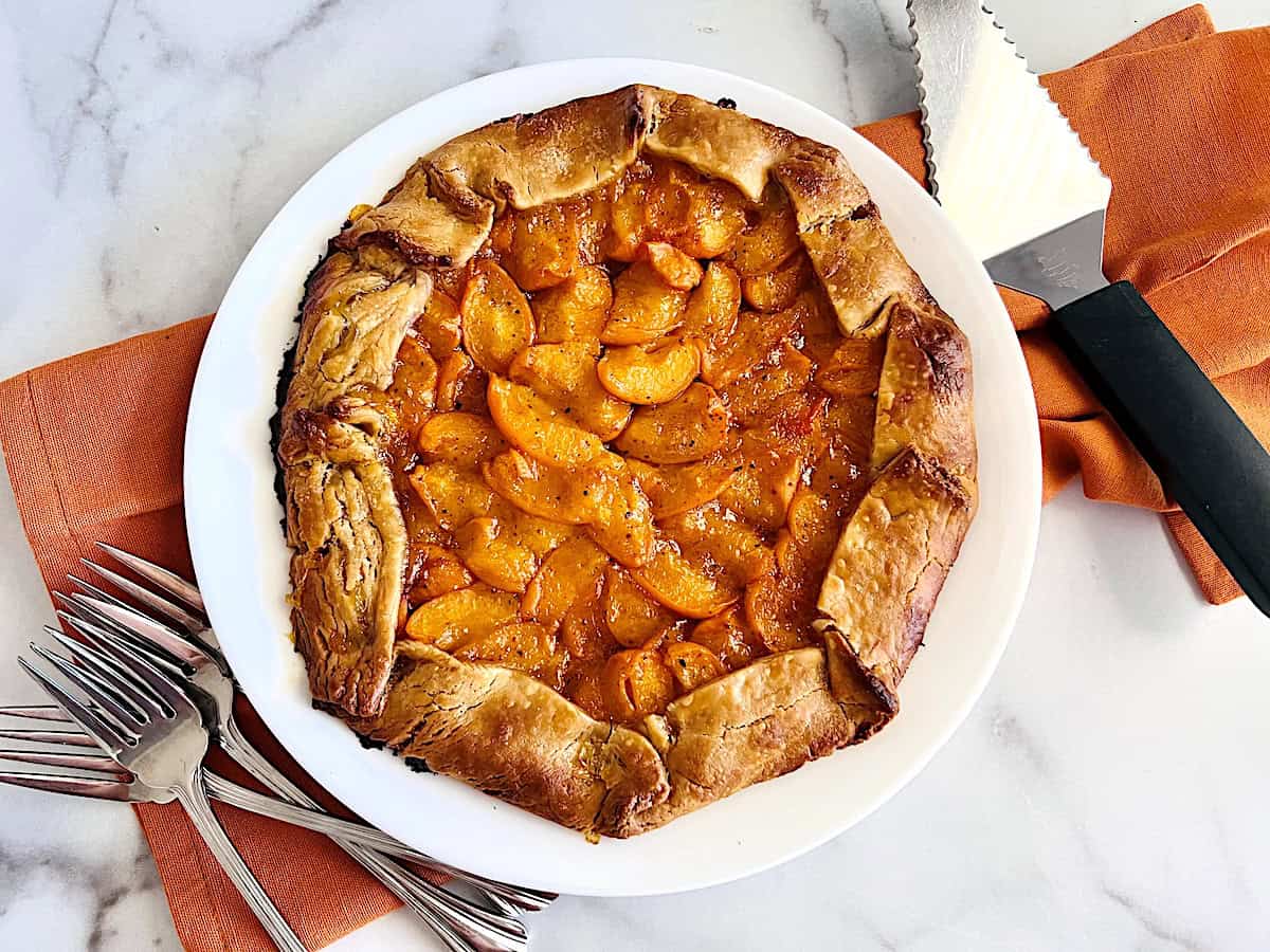 Golden brown pie crust in a freeform shape loaded with fresh apricot filling to make a galette from scratch. 