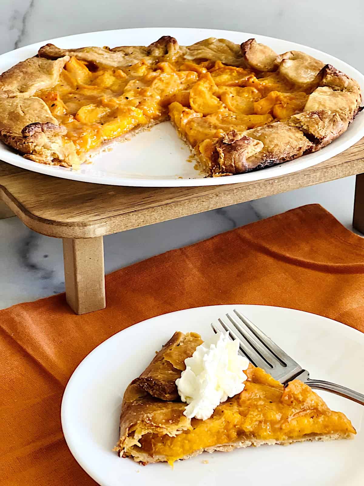 Easy Apricot Galette on a serving plate next to a slice with whipped cream plated to eat.