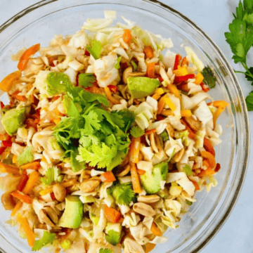 Bowl with cabbage avocado peanuts and asian coleslaw dressing.