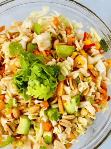 Bowl with cabbage avocado peanuts and asian coleslaw dressing.