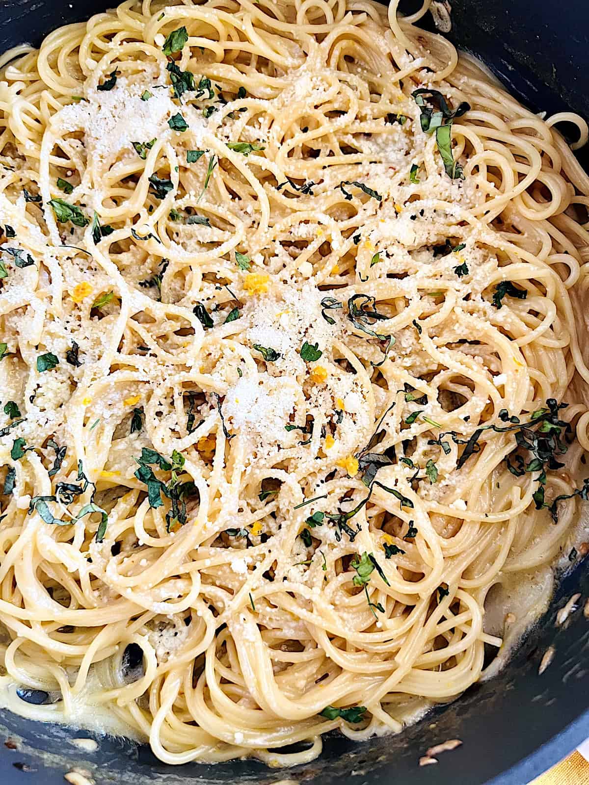 One Pot Lemon Butter Pasta (Pasta al Limone) Close up adding lemon zest fresh basil and parmesan to the top.