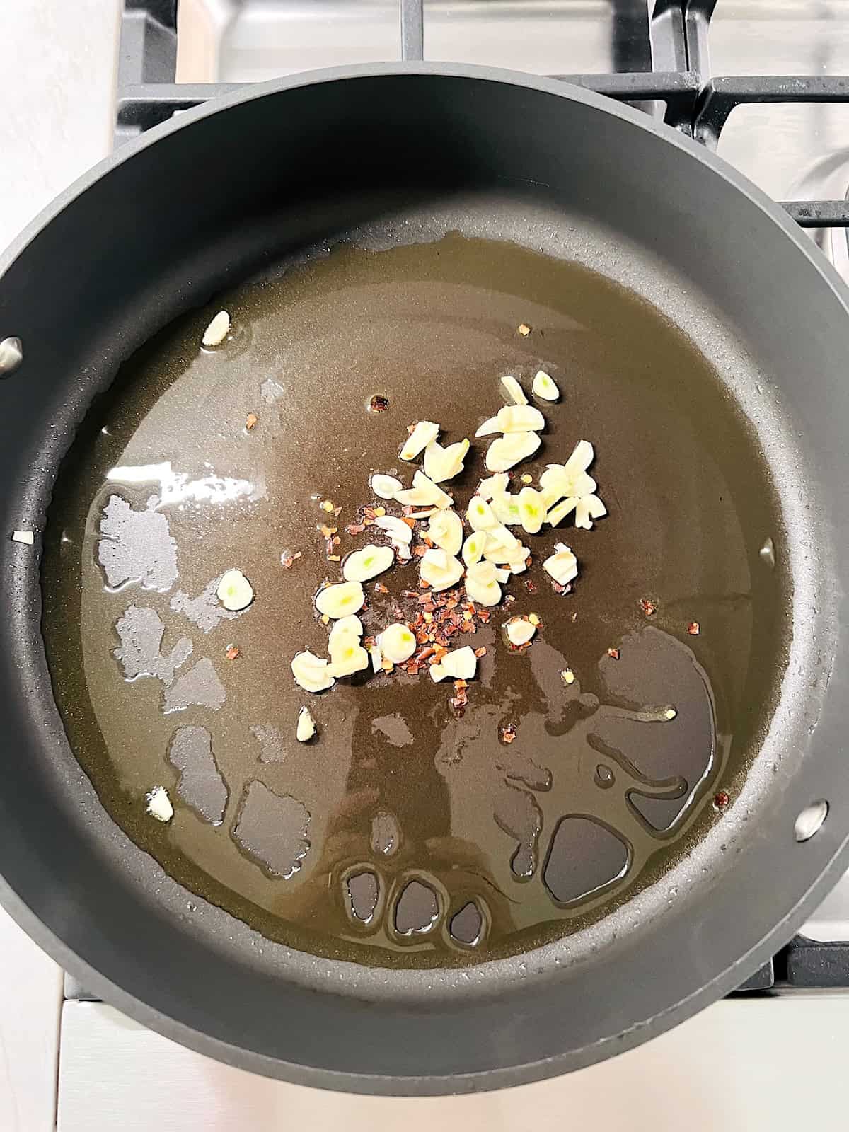 Olive oil sliced garlic and red pepper flakes in pot.