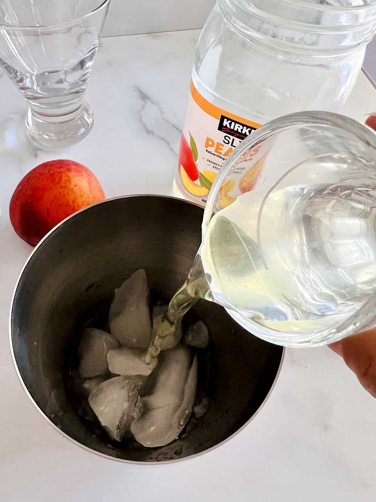 Peach Martini Adding ingredients to shaker with ice cubes.