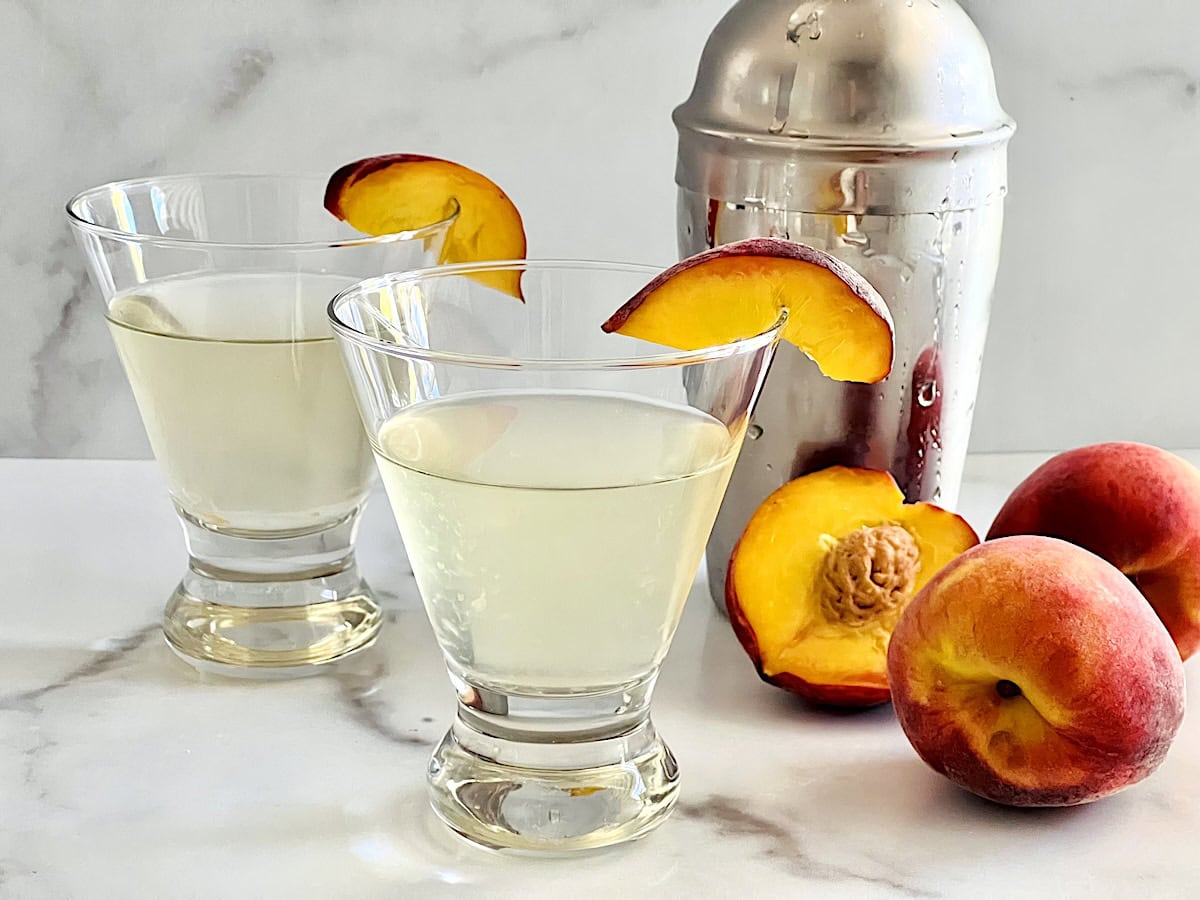 Two martini glasses with peach vodka and juice cocktails.