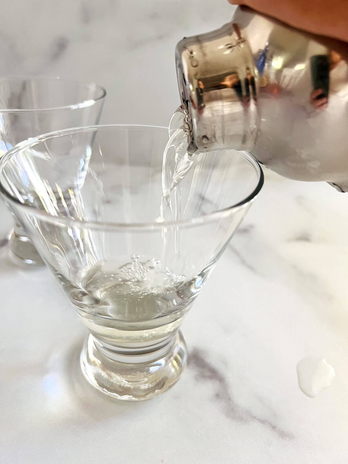 Pouring peach vodka and juices from the shaker into martini glass.