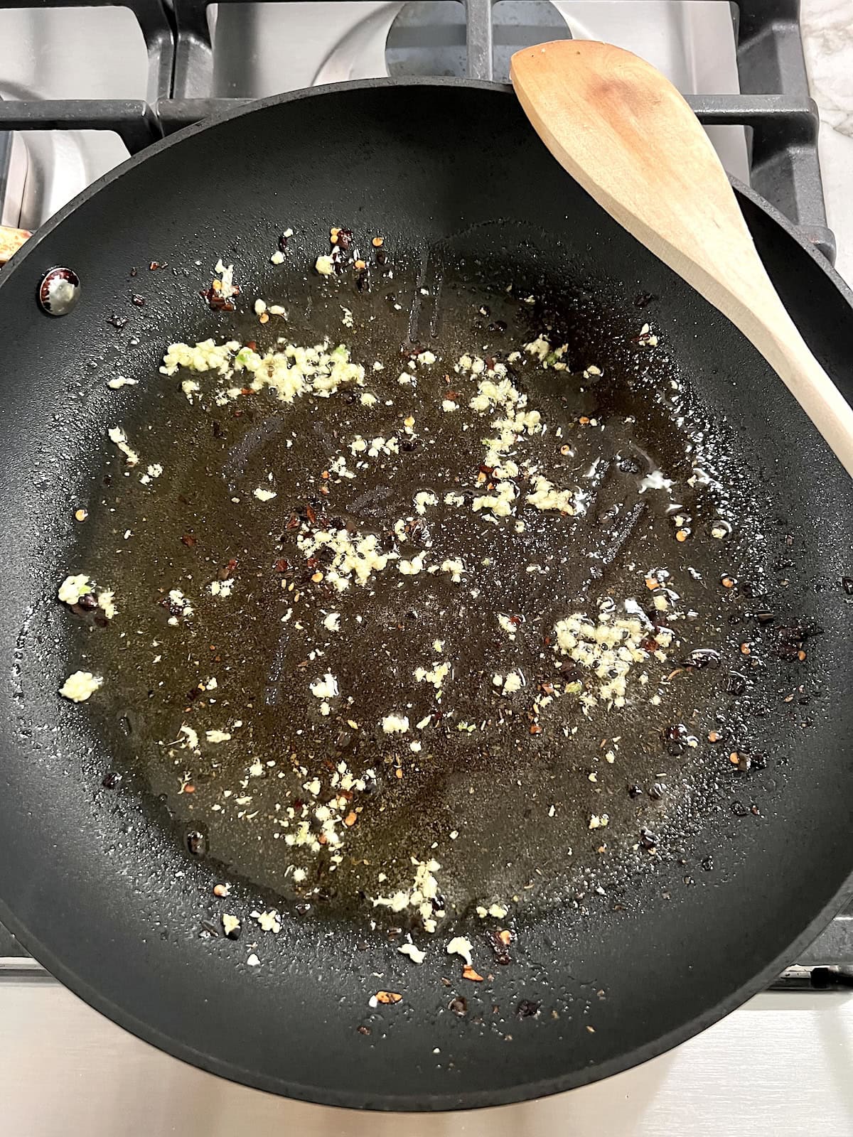 Cooking minced garlic in skillet with olive oil and spices.