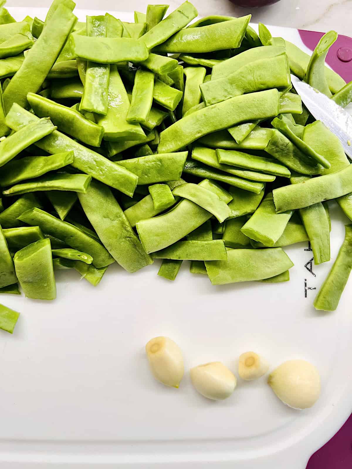 Cut beans and garlic on a board.