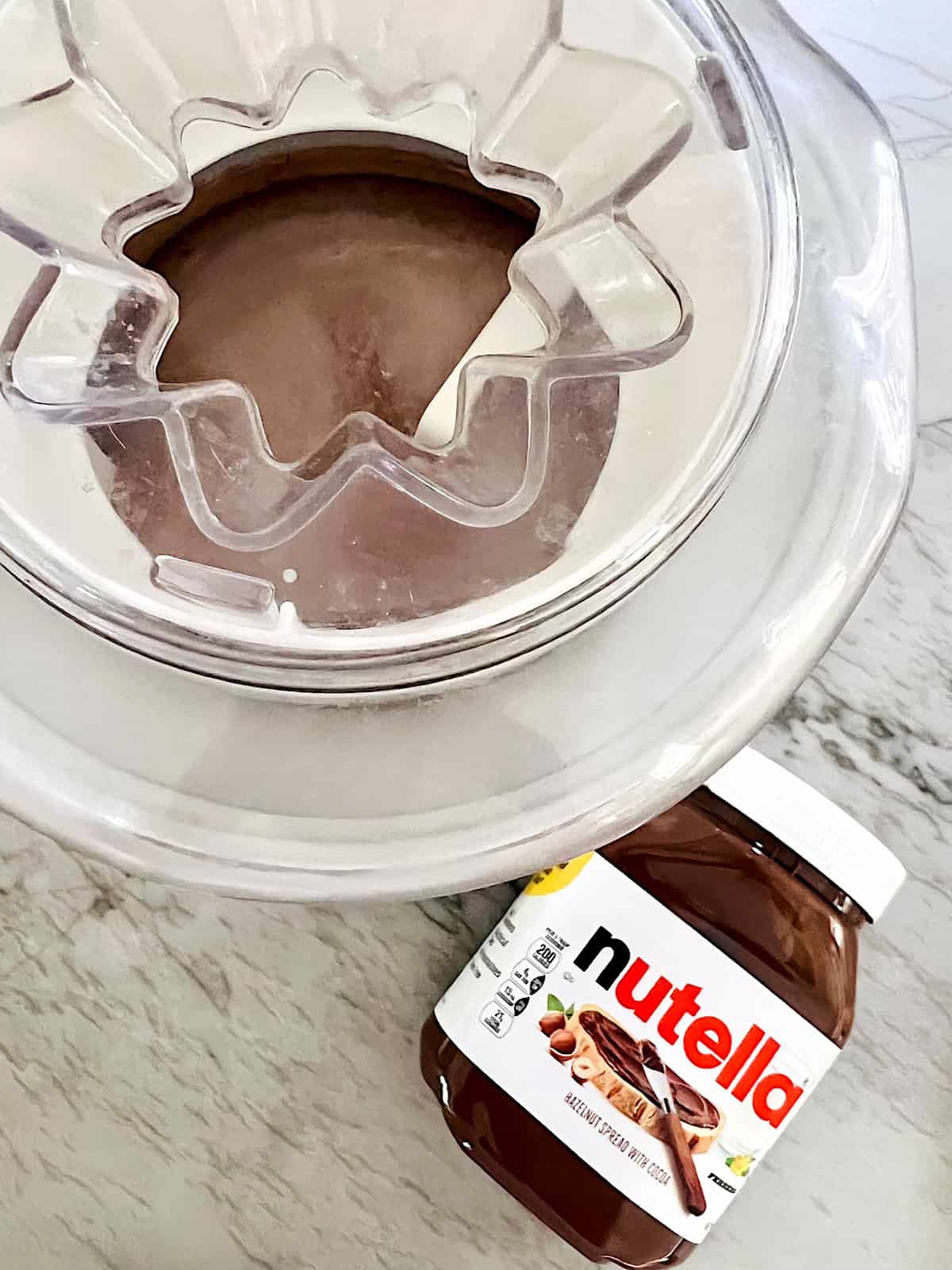Nutella Ice Cream Added to ice cream maker to churn next to jar of nutella spread.