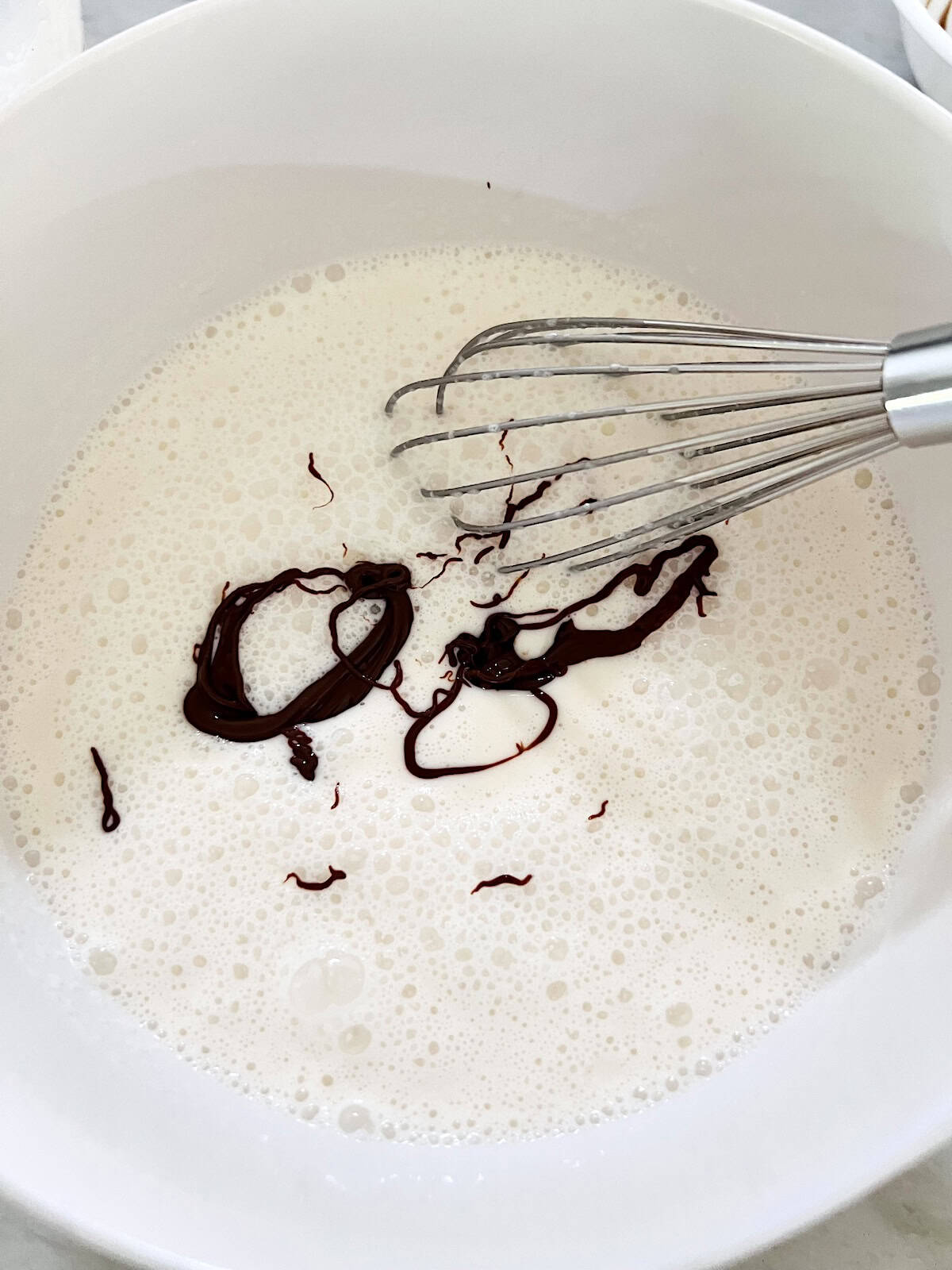 Bowl of vanilla ice cream base with nutella added ready to whisk.