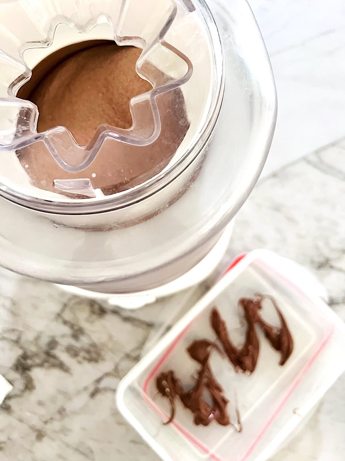 Nutella Ice Cream In Ice Cream maker ready to scoop into container showing streaks of Nutella in the bottom ready to top.