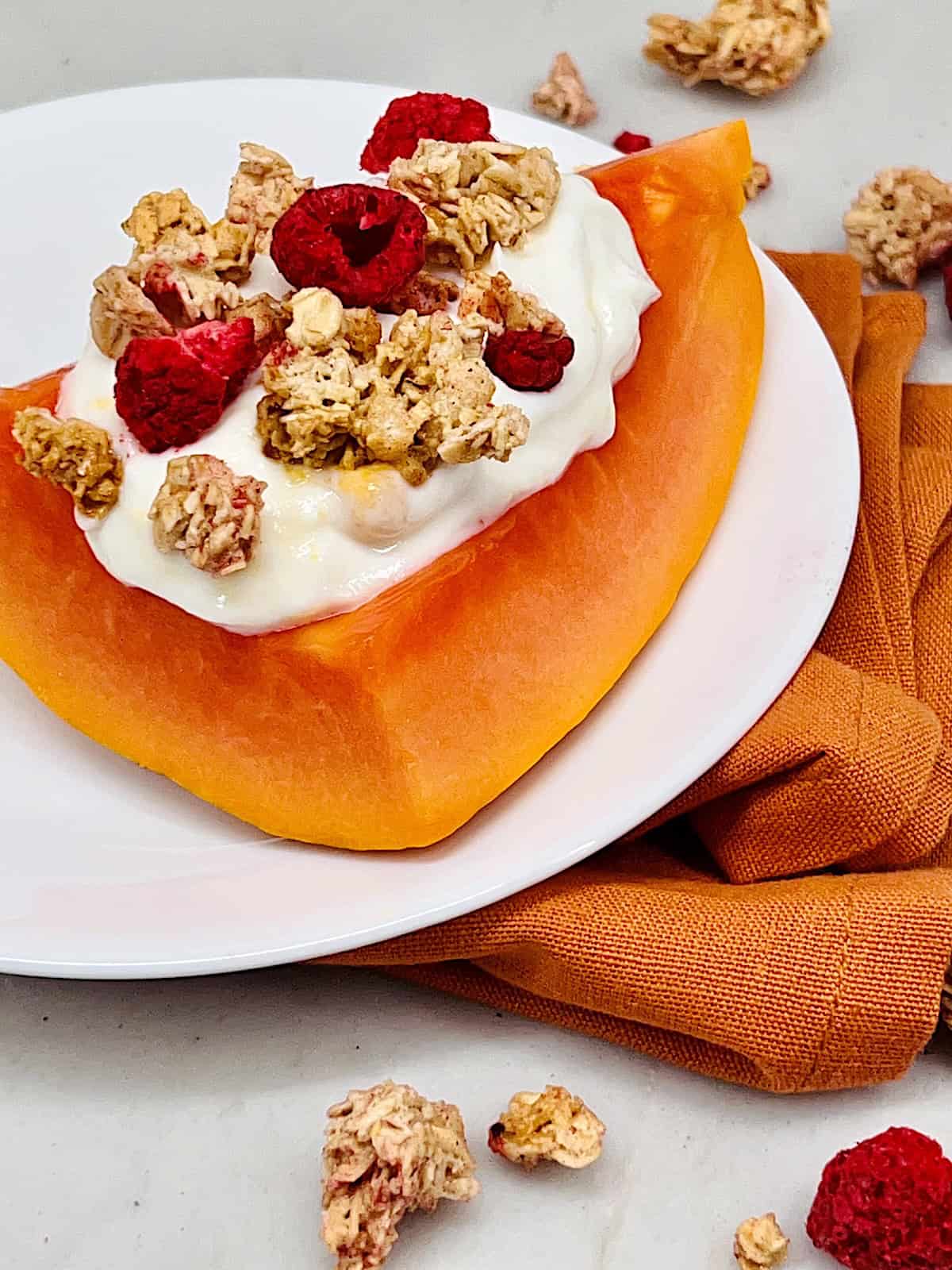Papaya Yogurt Boats Best recipe plated topped with granola and dried berries.