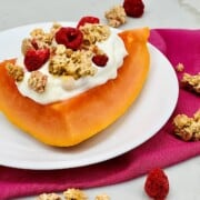 Fresh wedge of Papaya withYogurt creating a Boat topped with granola plated.
