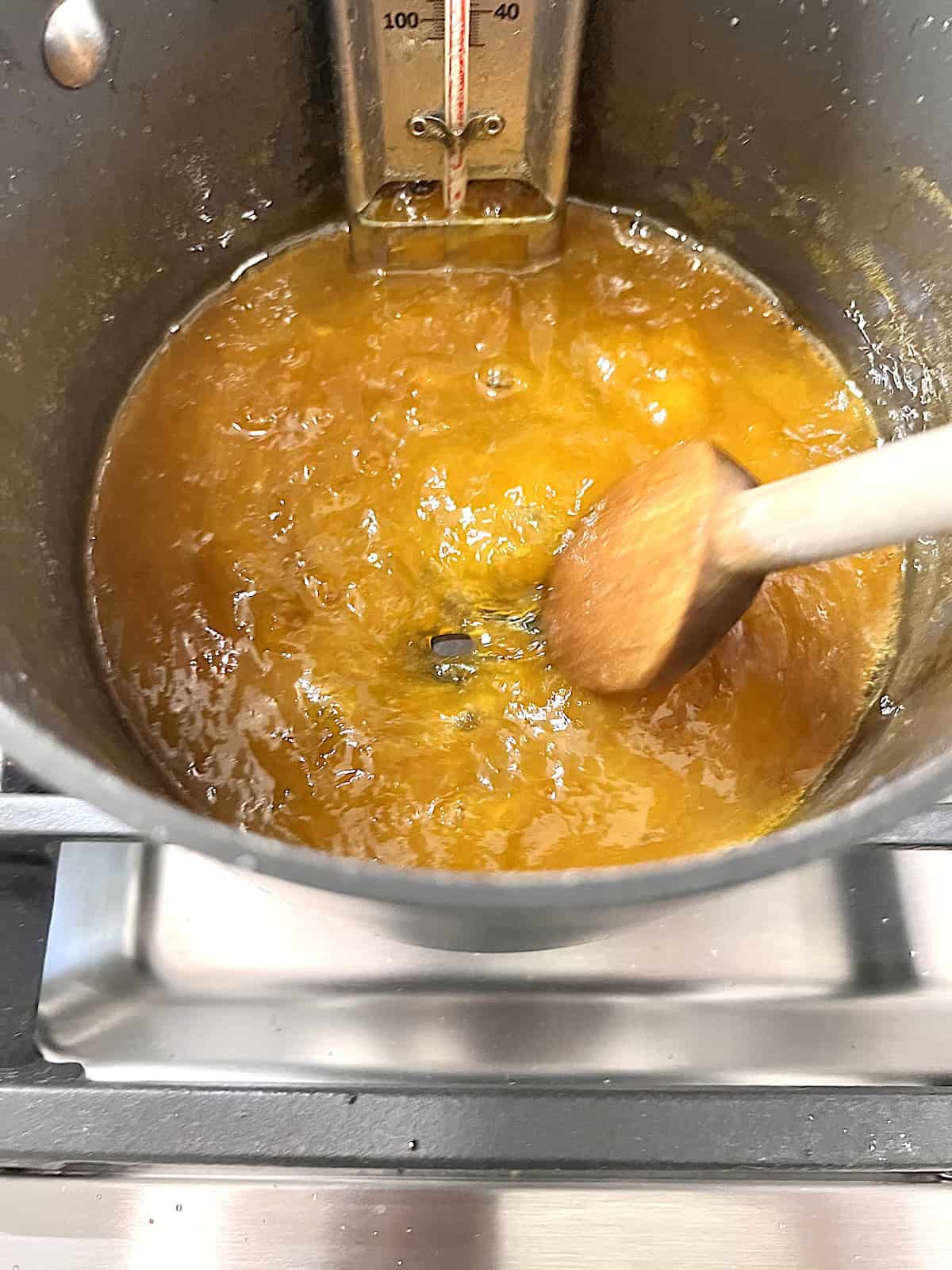 Plum Jam Wooden spoon along bottom of pot showing gelled fruit is ready.
