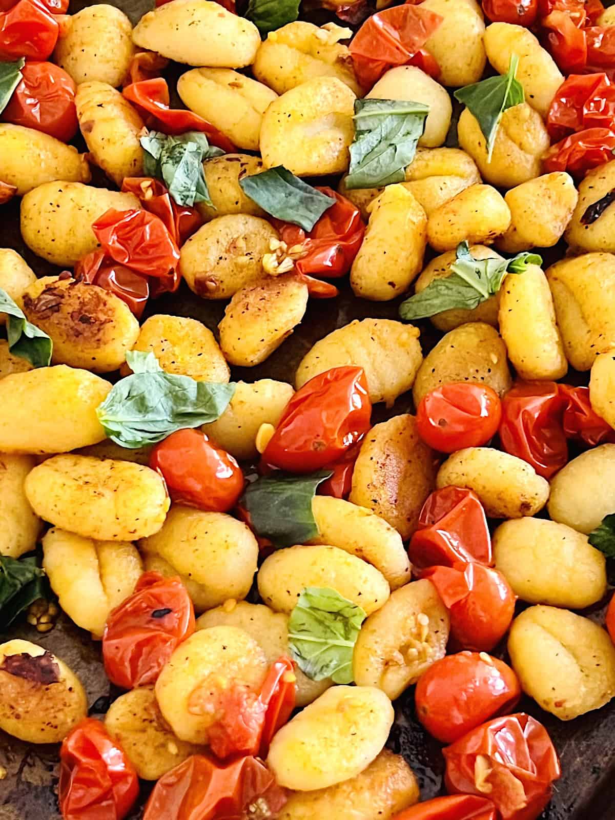 Sheet Pan Tomato Basil Gnocchi Closeup of cooked on the pan with crispy brown gnocchi and roasted bursted tomatoes.