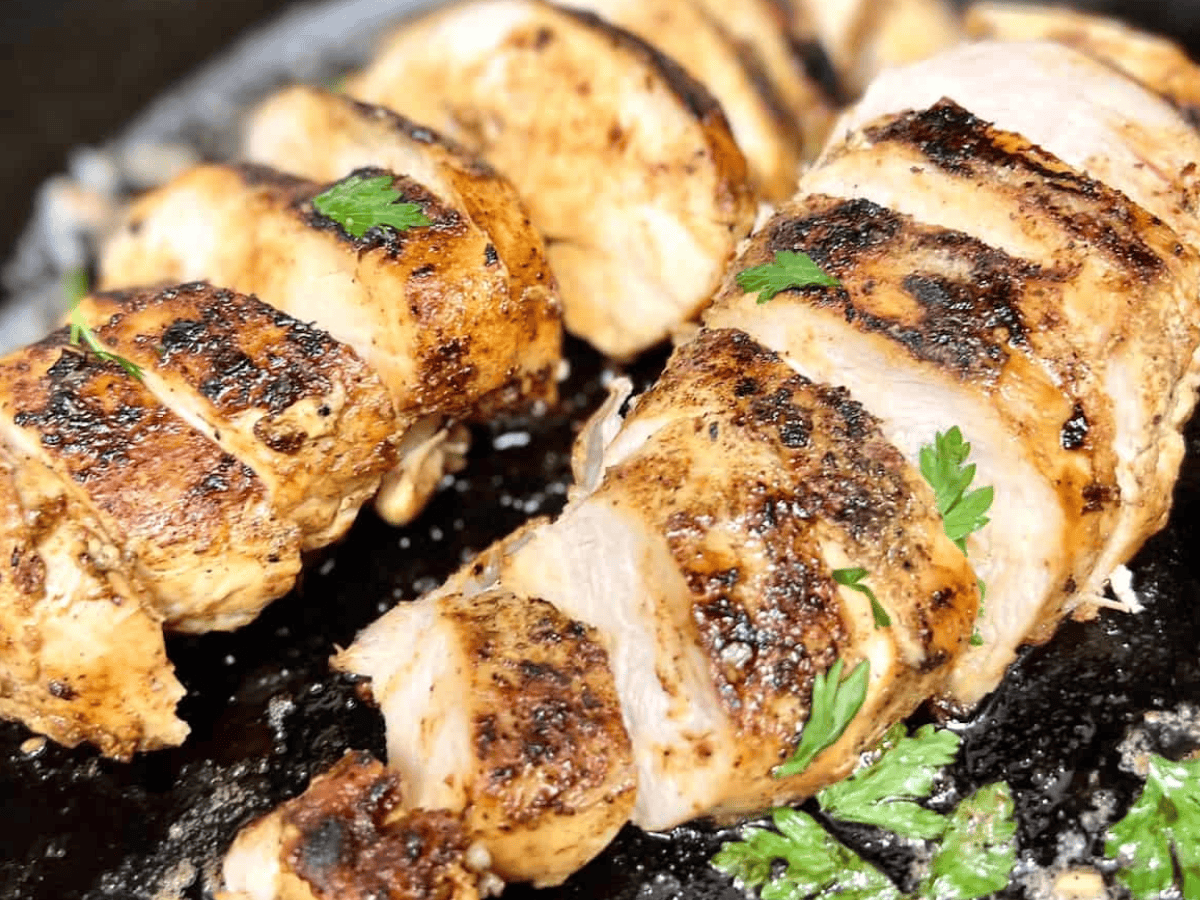 Sliced boneless skinless chicken breasts in a cast iron skillet with garlic butter sauce.