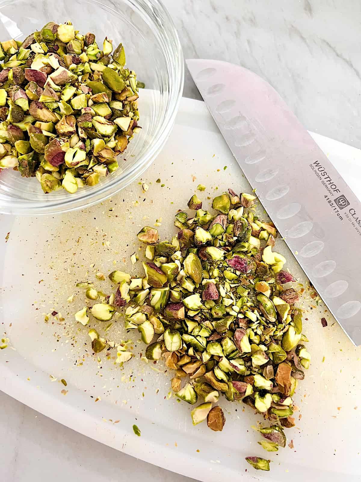 Pistachio Ice Cream Cutting board chefs knife and bowl with chopped nuts.