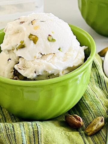 Pistachio Ice Cream scooped in a bowl loaded with nuts.