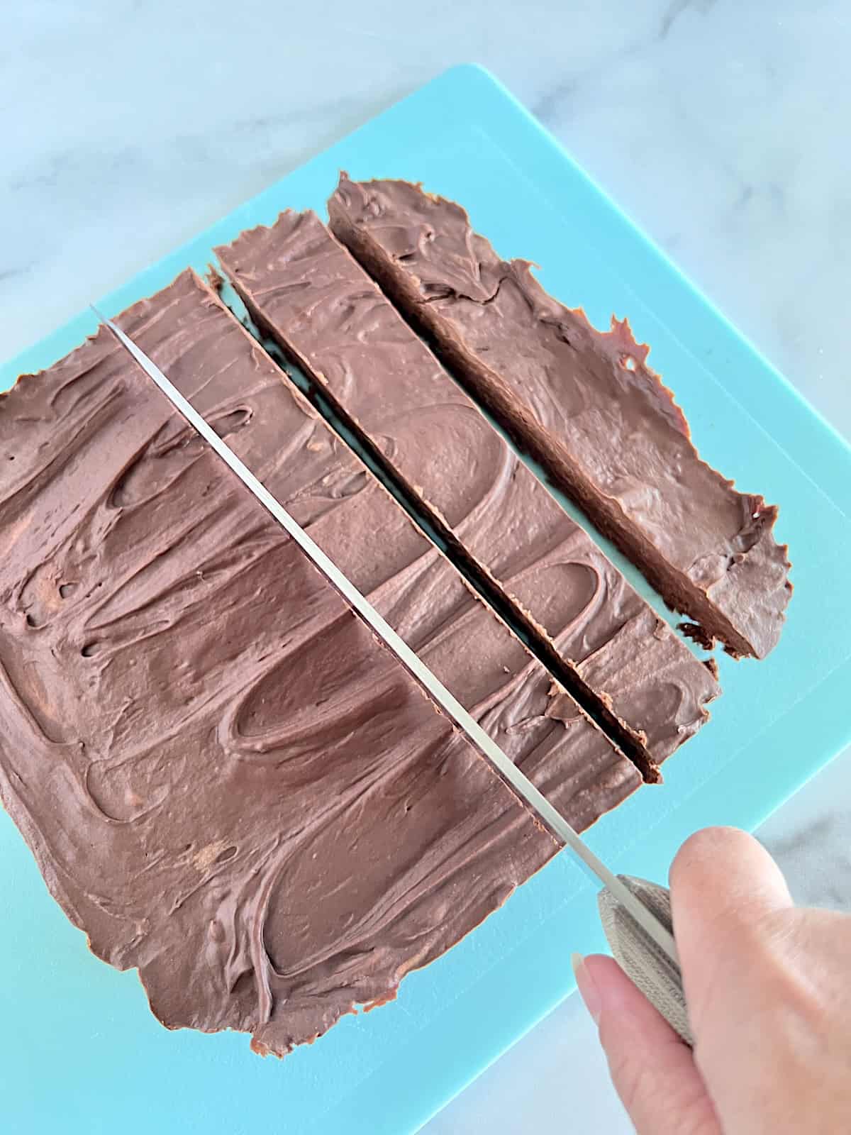 2 Ingredient Frosting Fudge Cutting into stips to make squares.
