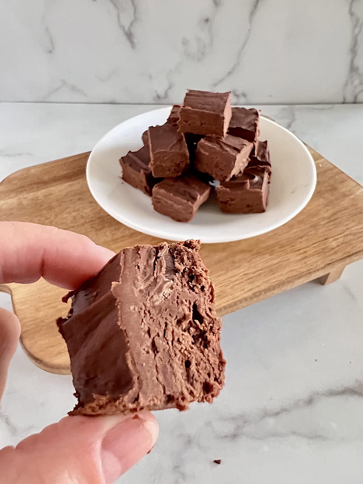 2 Ingredient Frosting Fudge Holding a piece up close.