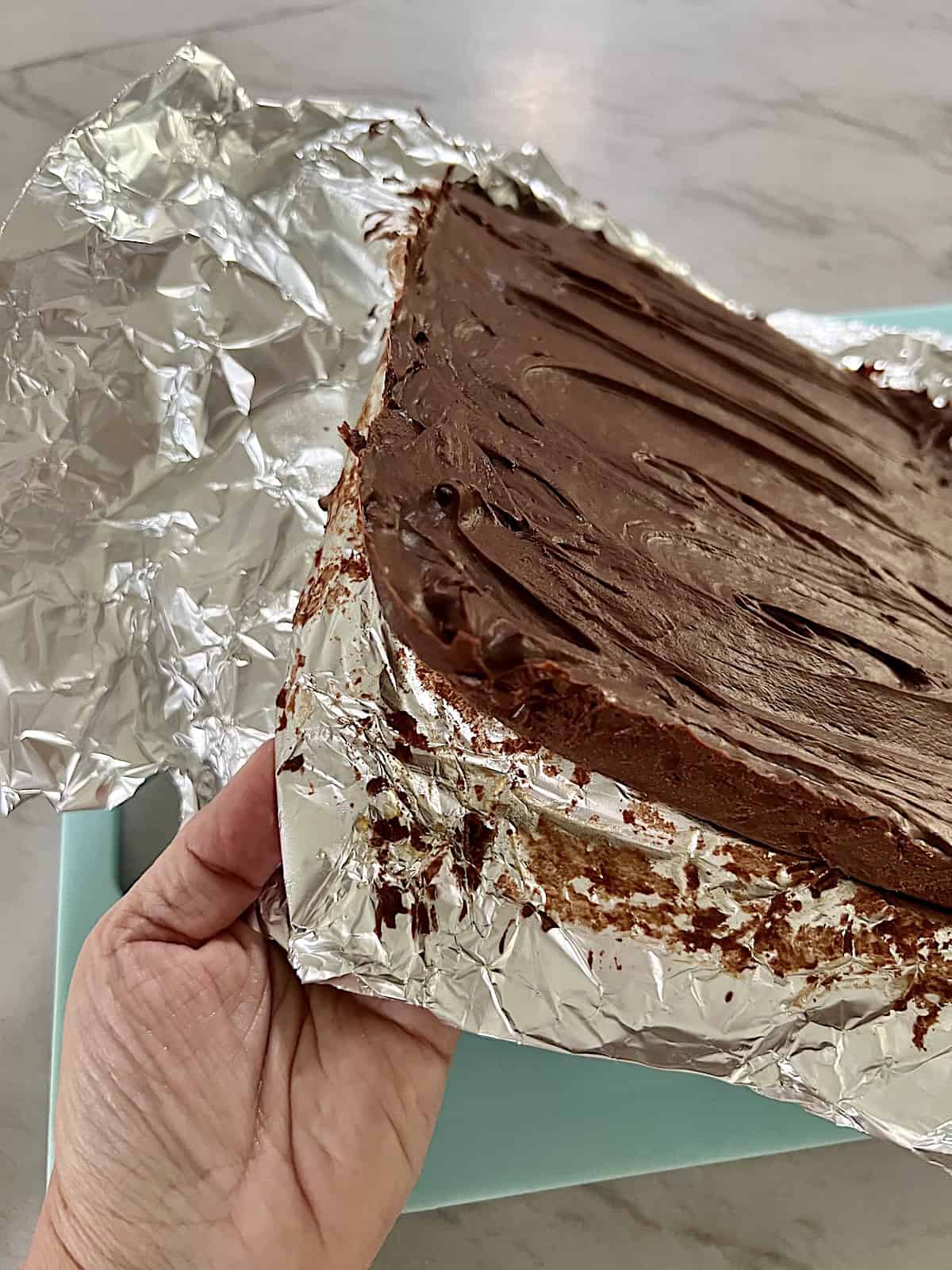 Peeling foil off the block of fudge.
