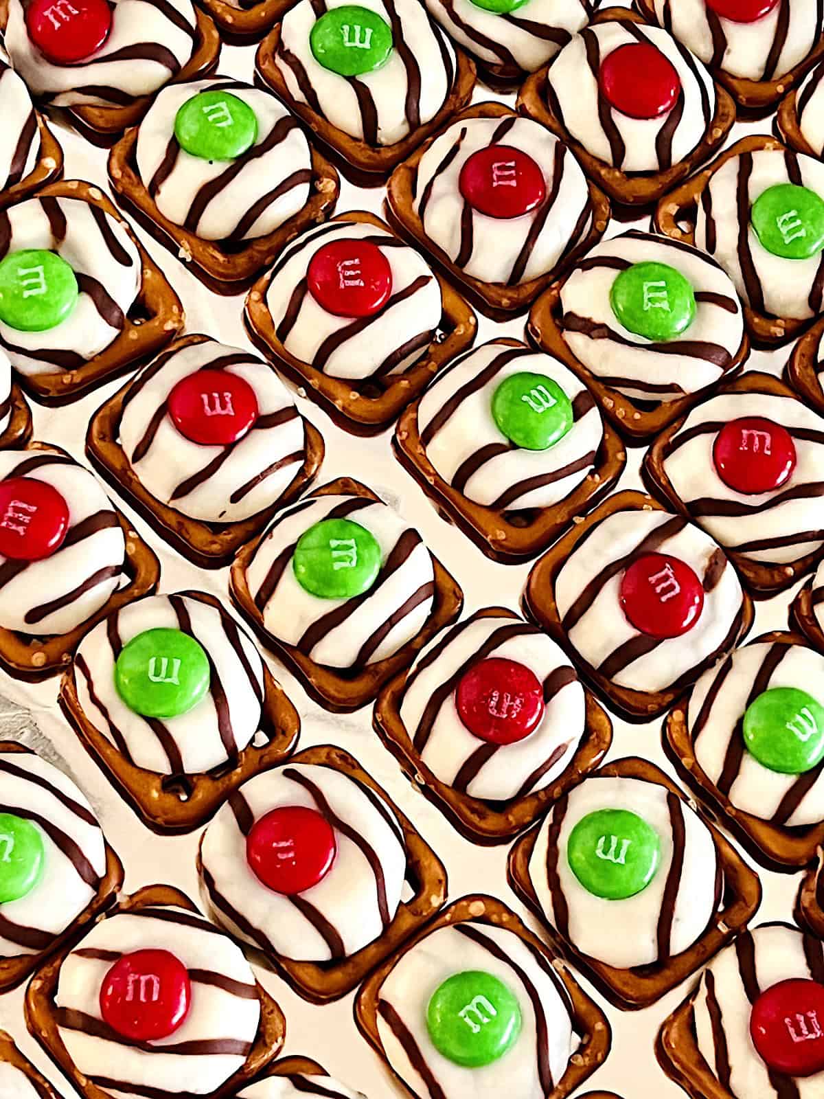 Christmas Pretzel Bites Closeup showing the striped Hershey's Hugs melted on Snyders snap pretzels topped with a red or green M&M.