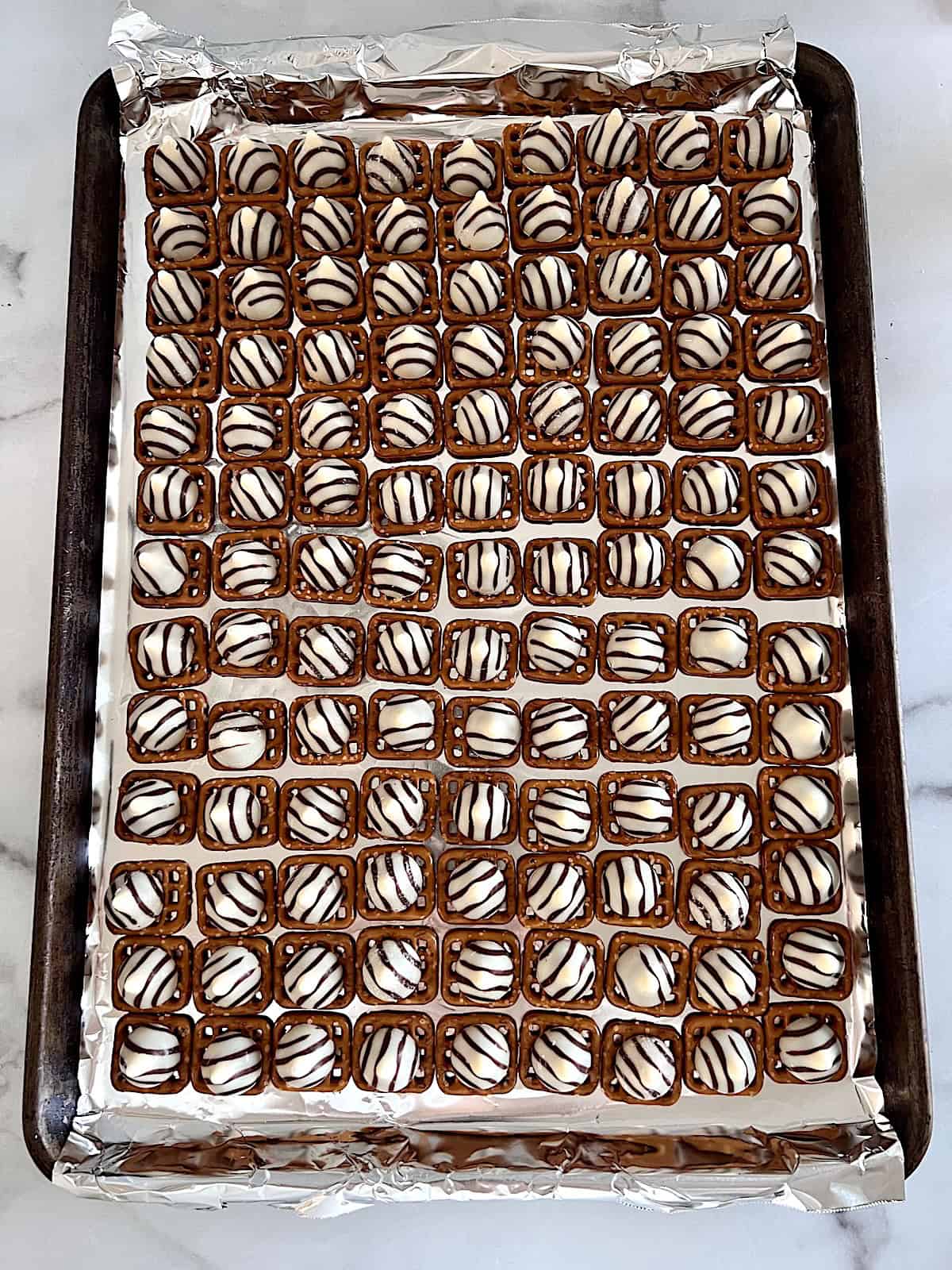 Snaps topped with Hersheys hugs on a sheet pan.