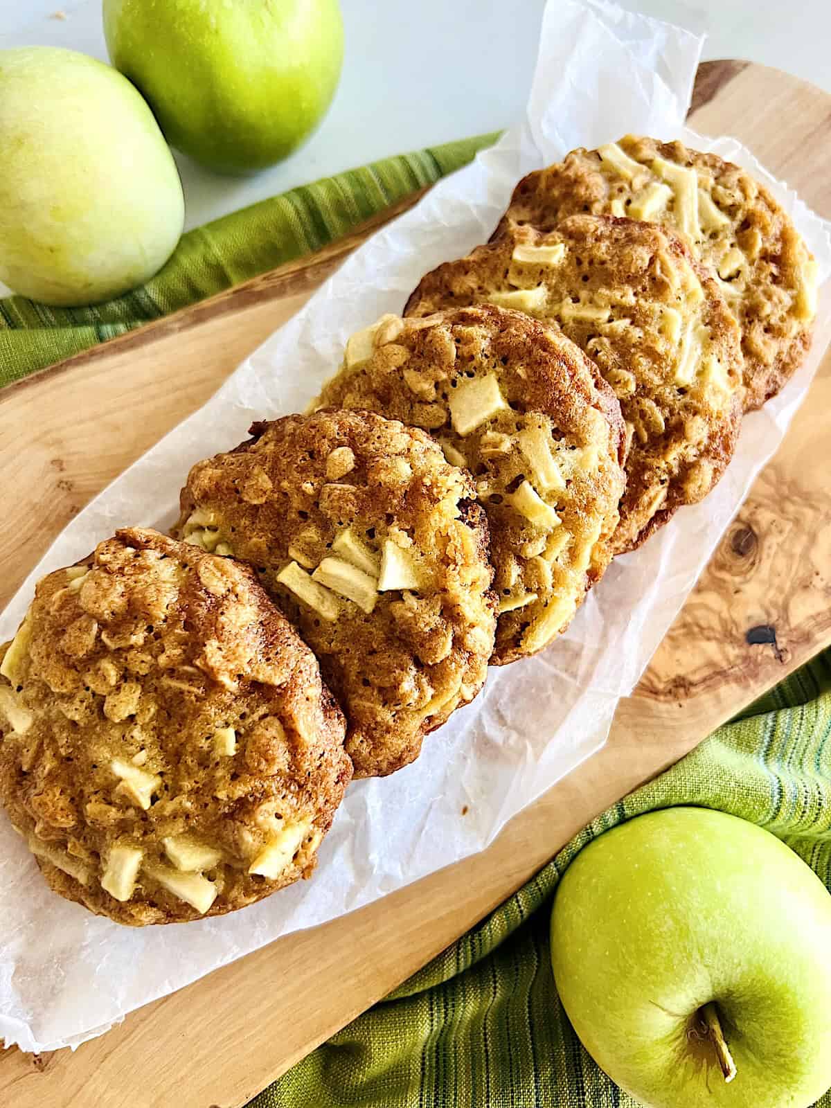 Soft and Chewy Apple Oatmeal Cookies Best Recipe cookies lined up on a board with parchment.