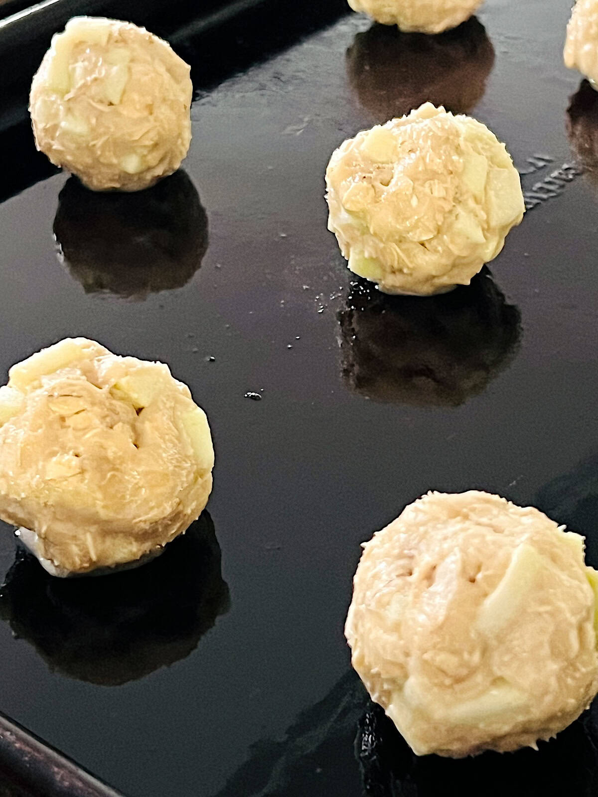 Cookies Dough Balls with apples and oats on a baking sheet.