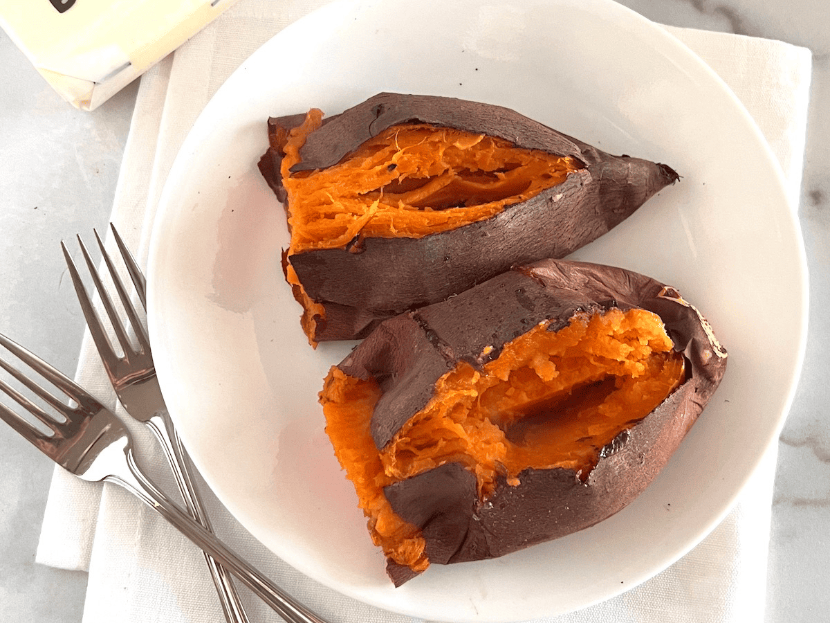 Oven Baked Sweet Potatoes cooked at 400°F plated with butter and forks ready to serve.