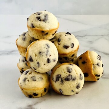 Mini Chocolate Chip Muffins stacked up on a white table