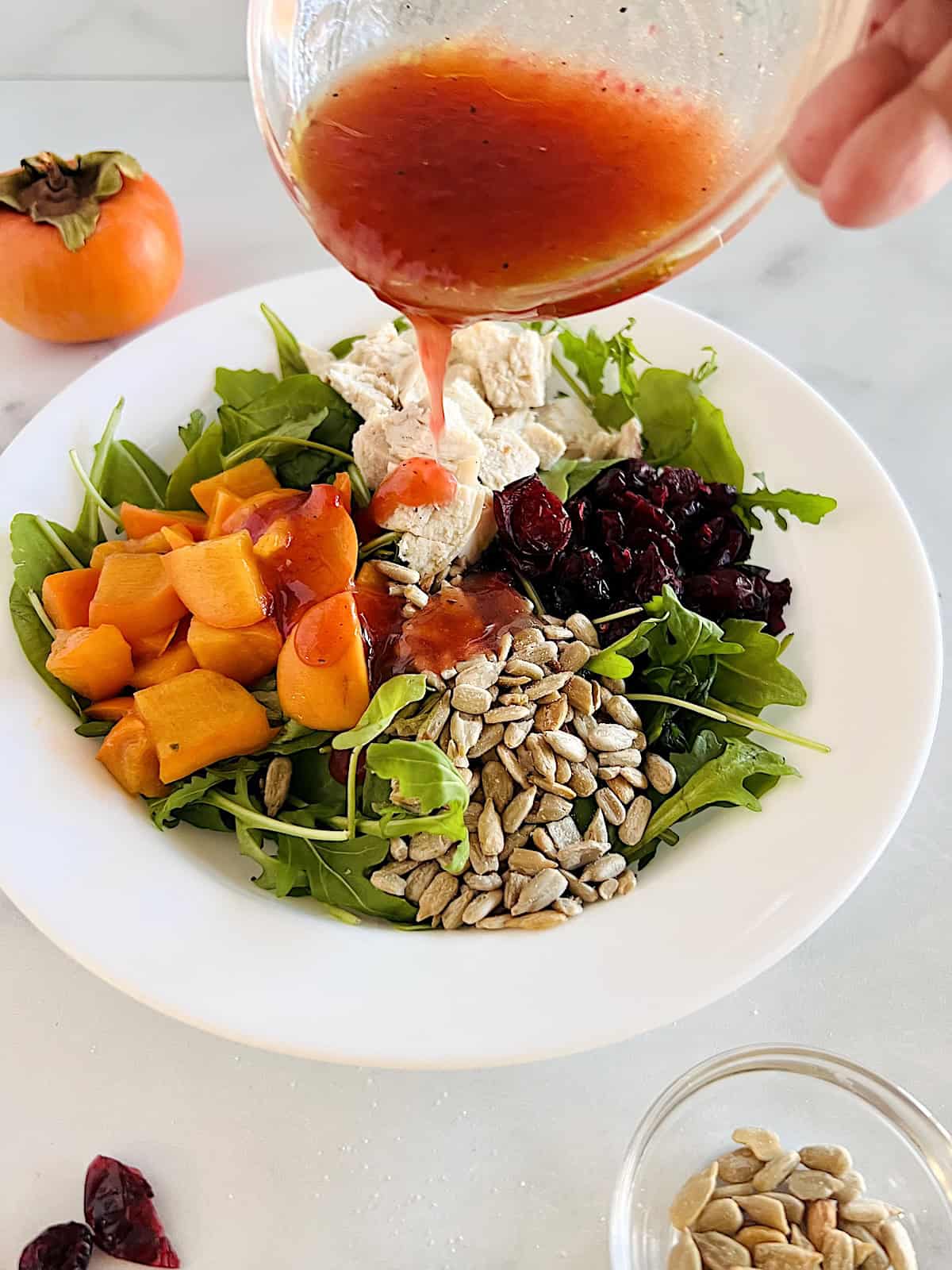 Winter Green Salad with Turkey Pouring dressing on the salad.