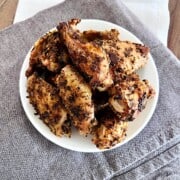 Plate of oven cooked chicken wings with crispy seasoned skin and no batter or flour.