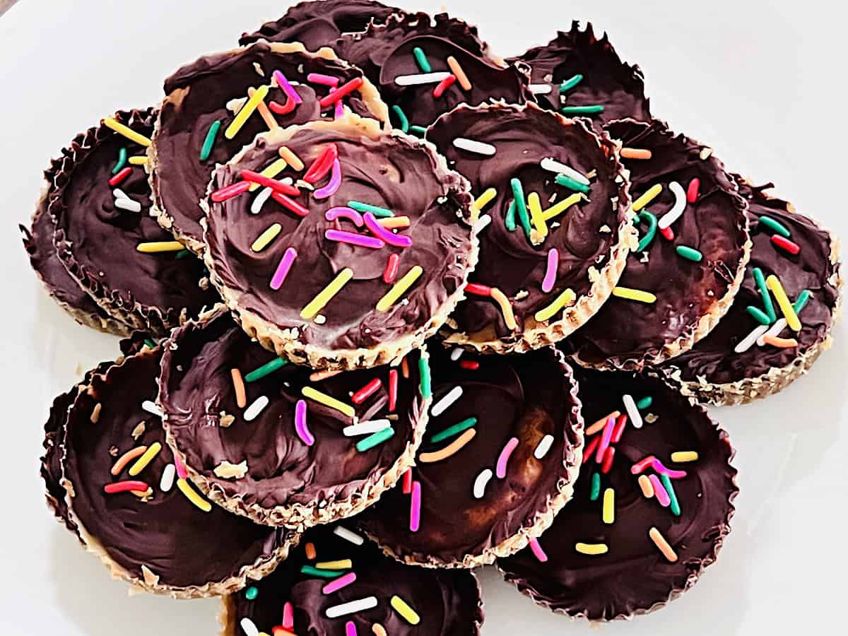 Ritz Cracker Toffee Cookies topped with semi sweet chocolate and sprinkles on a dessert plate.