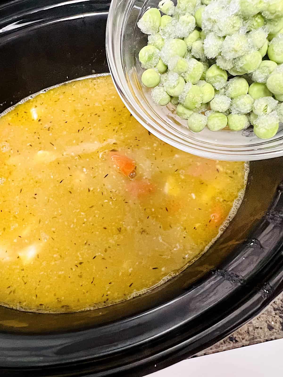 Adding peas to the chicken stew.