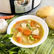 Slow Cooker Chicken Stew in a bowl with chunks of potatoes peas and carrots.