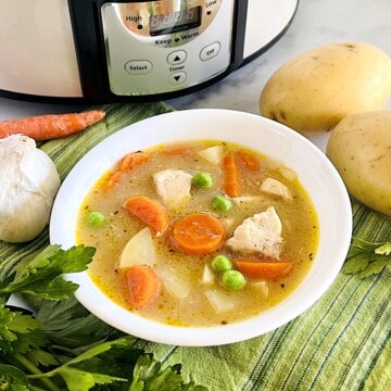 Slow Cooker Chicken Stew in a bowl with chunks of potatoes peas and carrots.