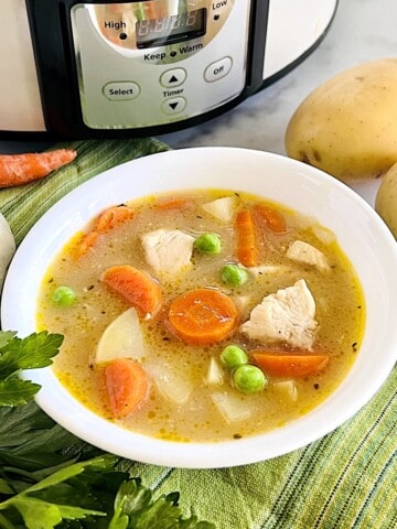 Slow Cooker Chicken Stew in a bowl with chunks of potatoes peas and carrots.
