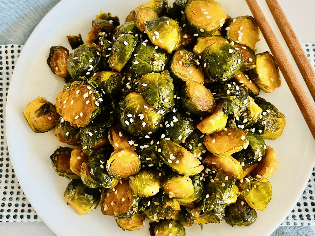 Plate of oven roasted asian Brussels sprouts with teriyaki sauce and sesame seeds