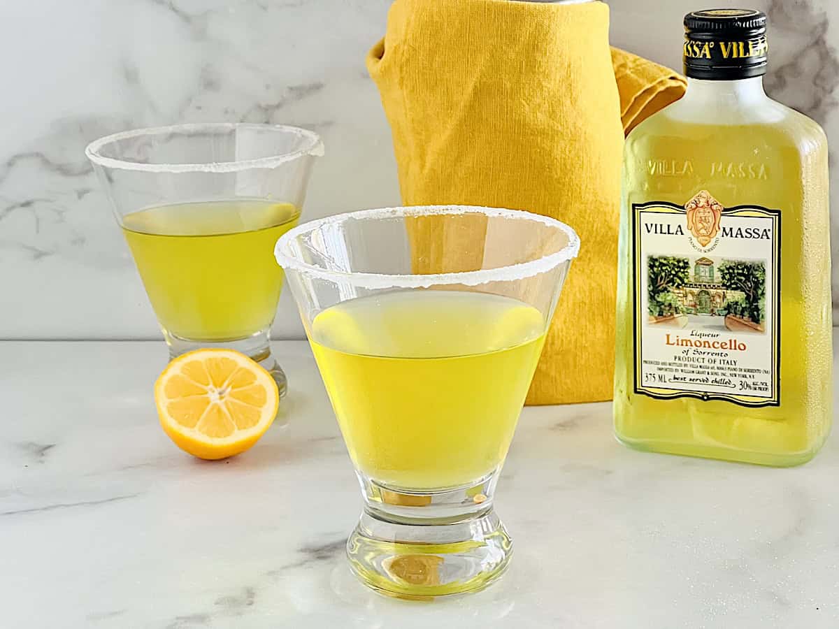 Lemon Drop Martini with Limoncello bottle and cut fresh lemons.