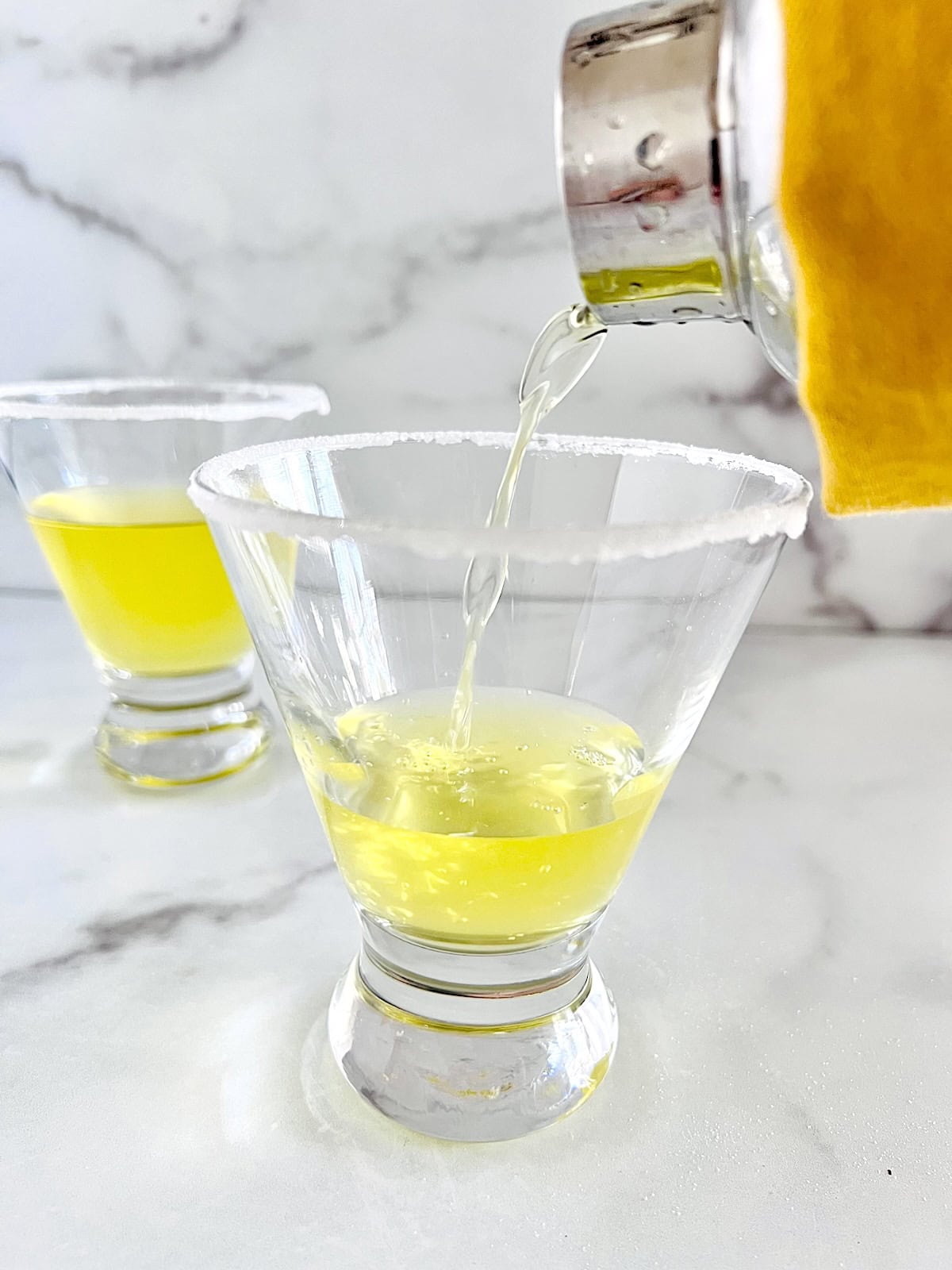 Lemon Drop Martini with Limoncello Pouring into sugar rimmed martini glasses from shaker.