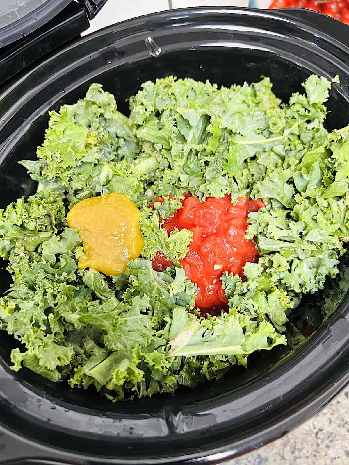 Slow Cooker Sausage Kale Soup Adding kale tomatoes and bouillon to crockpot.