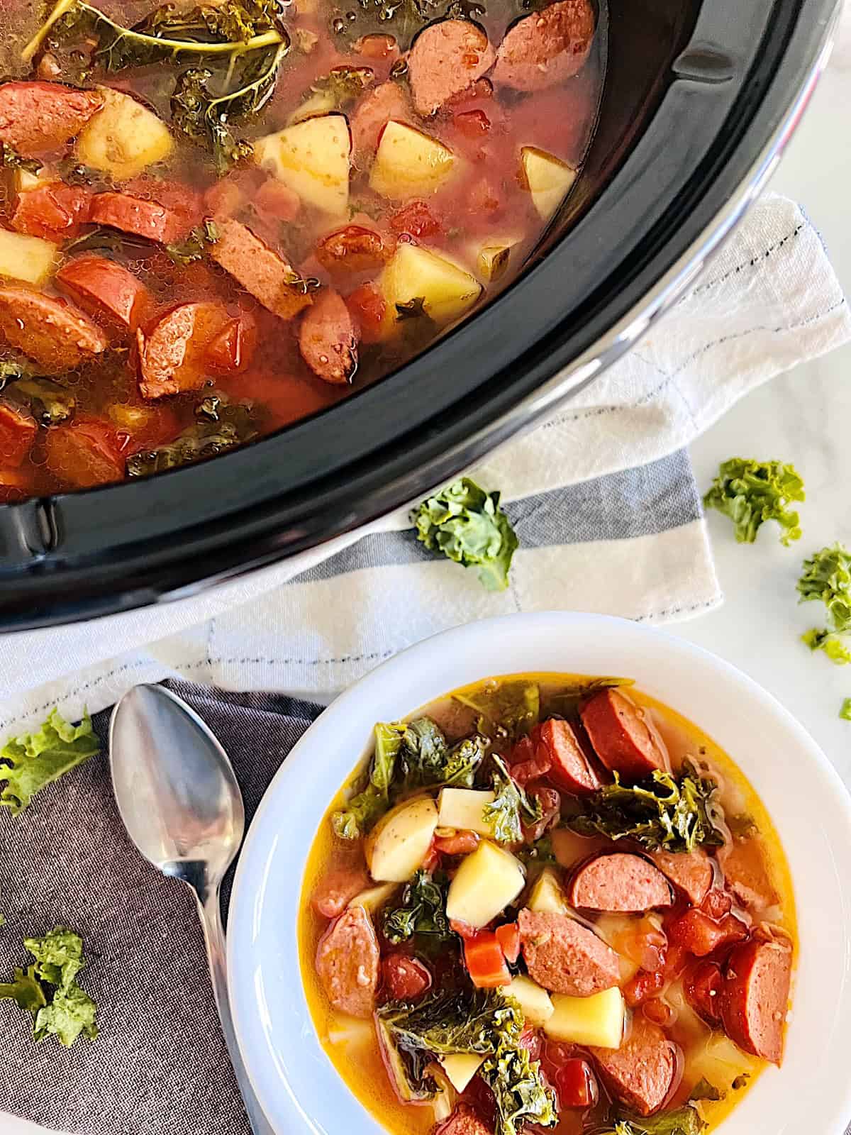 Slow Cooker Sausage Kale Soup Crockpot full of homemade soup next to bowl filled ready to eat