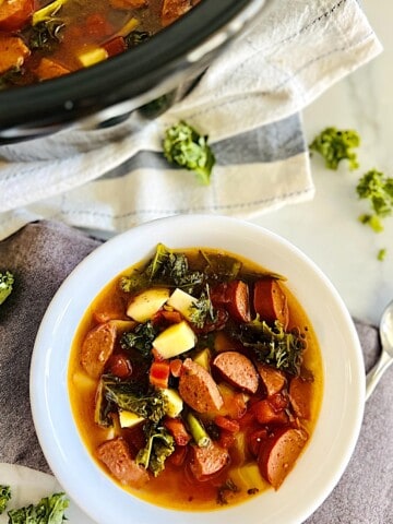 Slow Cooker Sausage Kale Soup with potatoes In crockpot and bowl ready to eat.
