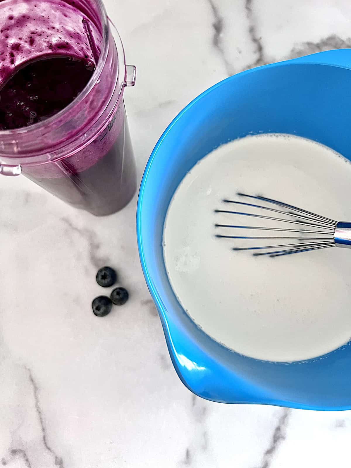 Vanilla base in a bowl next to pureed blueberries.