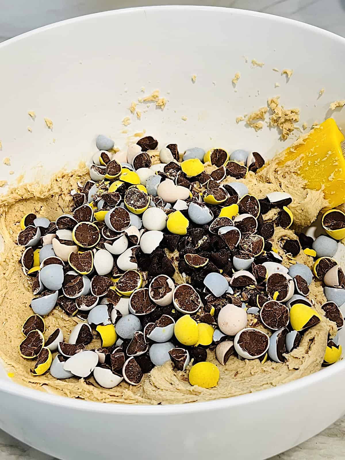 Folding in chocolate chips and Cadbury mini eggs into cookie dough.