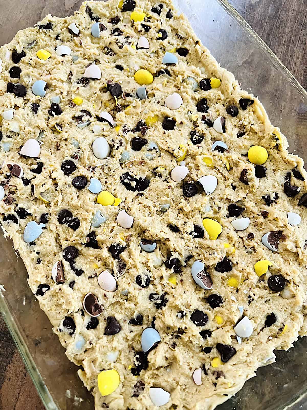 Cadbury Mini Egg Cookie Bars Spread in 9x12 pan topped with more Cadbury mini eggs.